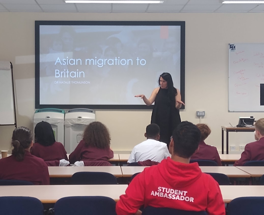 Dr Nataie Thomlinson standing in front of a screen

Description automatically generated